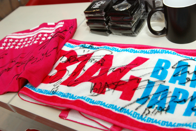 B1A4メンバー直筆サイン入りタオル(右)と店内展示のTシャツ(左)